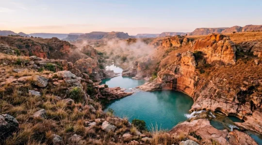 Vue panoramique des piscines naturelles cristallines de l'Isalo au lever du soleil avec formations rocheuses dorées